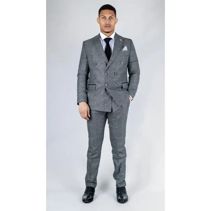 Model dressed in a sophisticated grey checkered suit with a double-breasted blazer, white shirt, and black tie, standing outdoors.