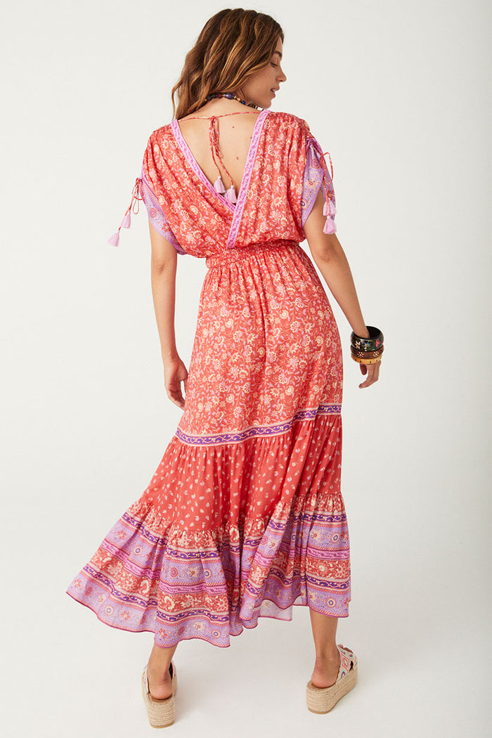Back view of Sunshine Bandit Gown in Cayenne, showing deep V-back, tassel neck tie, and tiered border-print hem