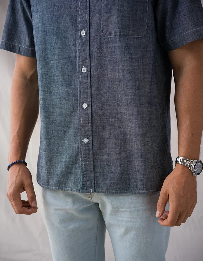 Close-up of Ace Rivington Surplus Chambray shirt torso showing button placket, chest pocket, and indigo cotton chambray fabric texture