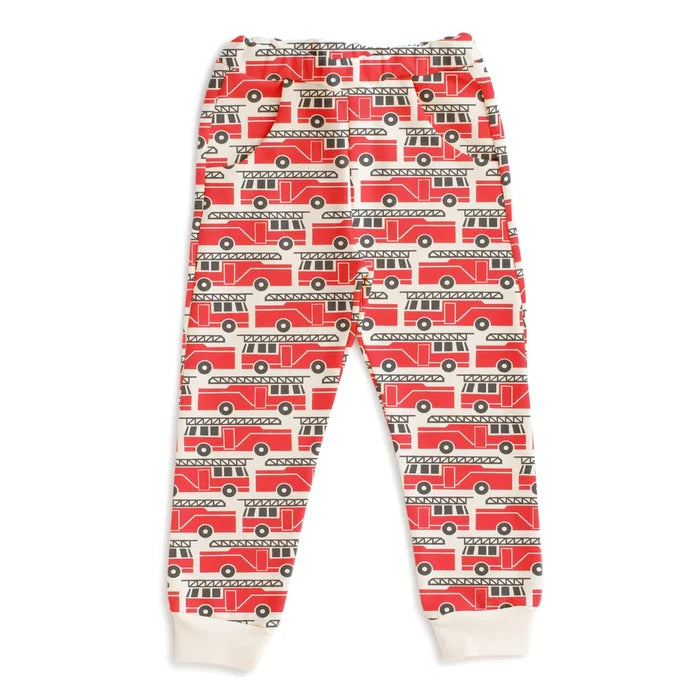 A pair of children's jogger pants featuring an all-over red fire truck pattern on a white background, with white ribbed cuffs at the ankles.