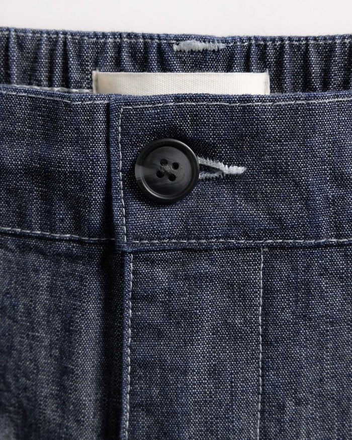 Close-up of a button on a denim fabric pocket with a white background
