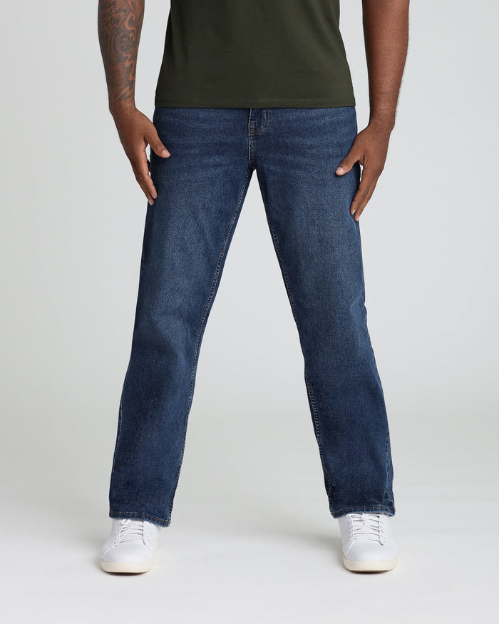 Man wearing medium blue straight-leg jeans and olive-green t-shirt with white sneakers.