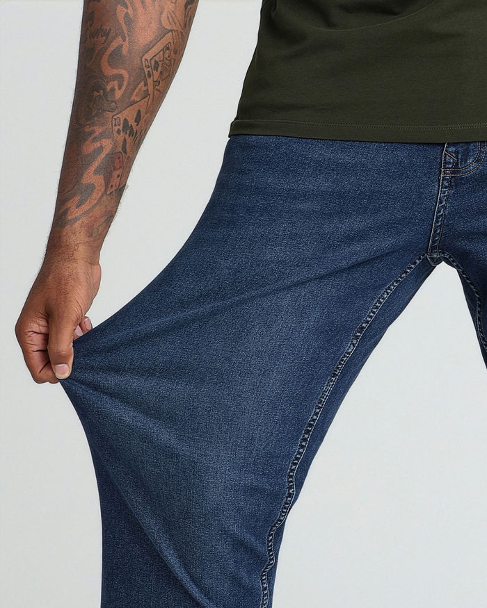 Model wearing medium blue denim jeans with olive-green t-shirt, demonstrating fit and fabric.