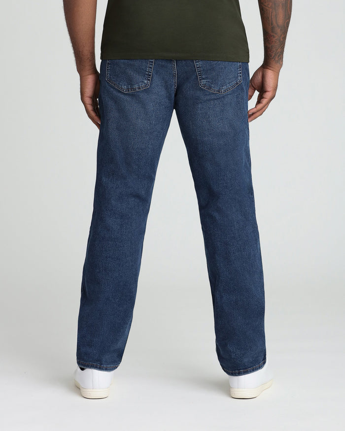 Man wearing medium blue straight-fit jeans with a dark olive t-shirt, shown from behind.