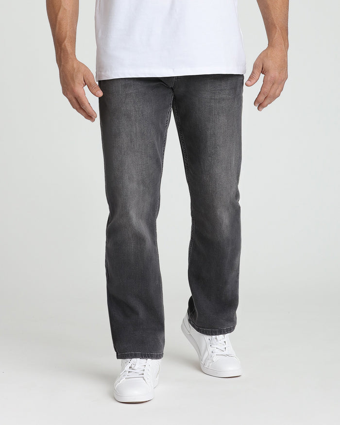 Man wearing white t-shirt and charcoal straight-leg jeans with white sneakers.