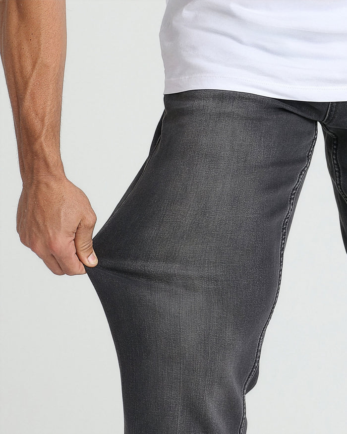 Charcoal grey denim jeans with relaxed fit shown on model wearing white t-shirt.