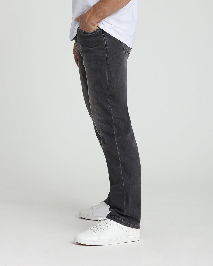 Charcoal grey relaxed-fit jeans with straight leg on model wearing white t-shirt and white sneakers.