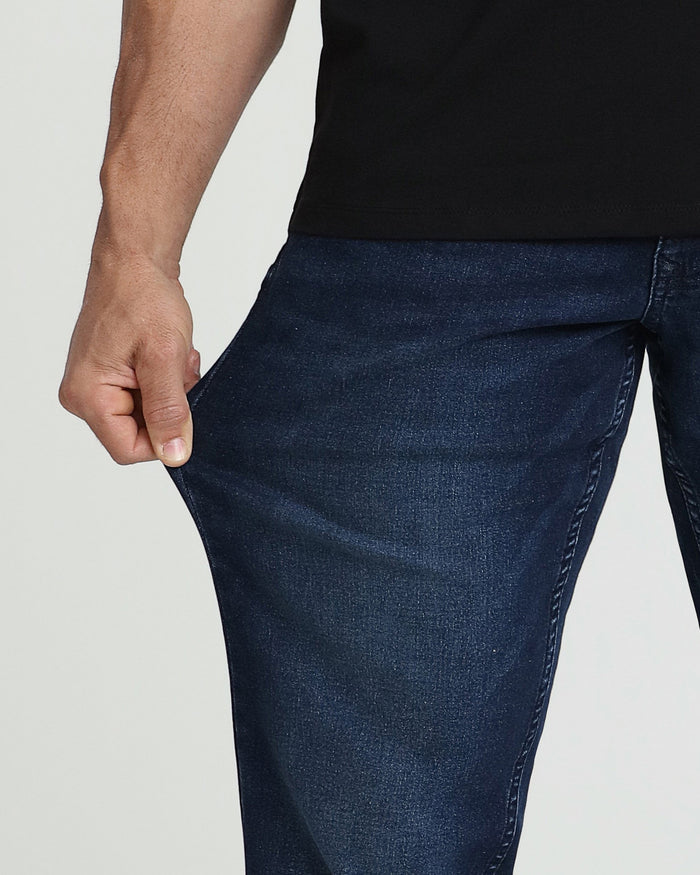 Man wearing black shirt and dark blue denim pants with relaxed thigh fit.