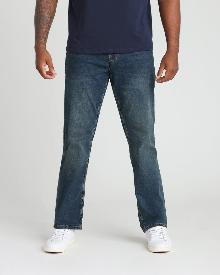 Man wearing navy t-shirt and medium-wash straight-leg jeans with white sneakers.