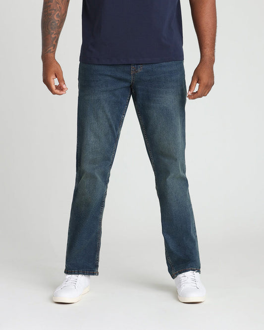 Man wearing navy t-shirt and medium-wash straight-leg jeans with white sneakers.