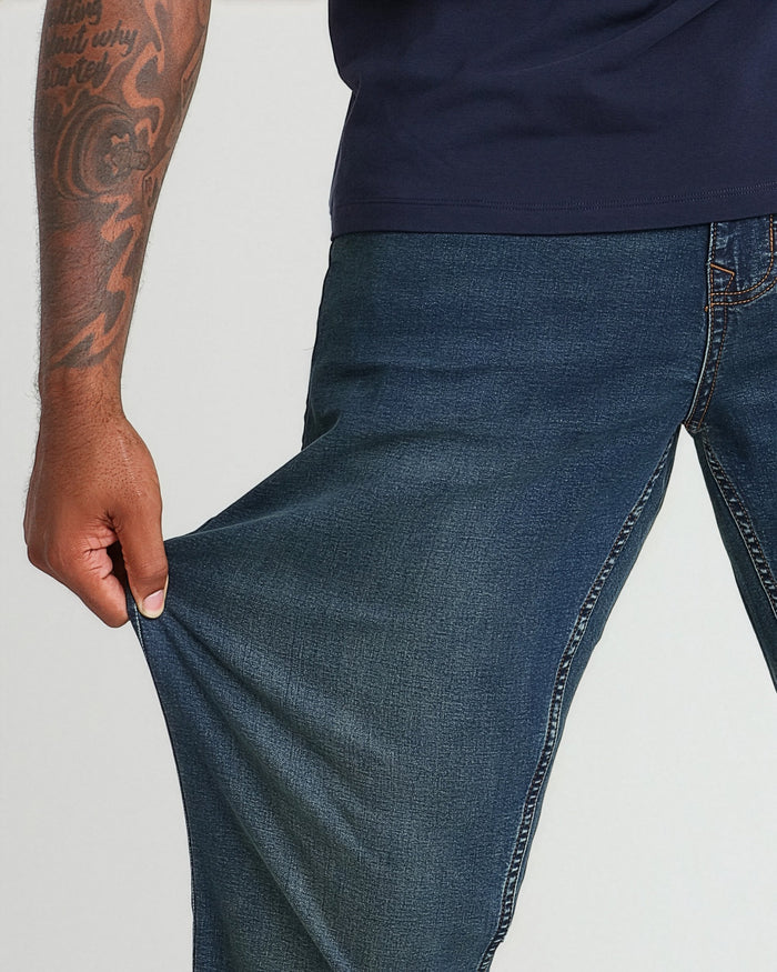 Dark tinted cowboy jeans with relaxed fit shown on model wearing navy shirt, displaying fabric texture and thigh width.