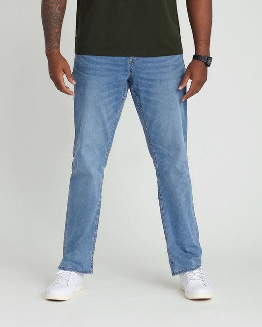 Light indigo bootcut jeans on model wearing olive green shirt and white sneakers.