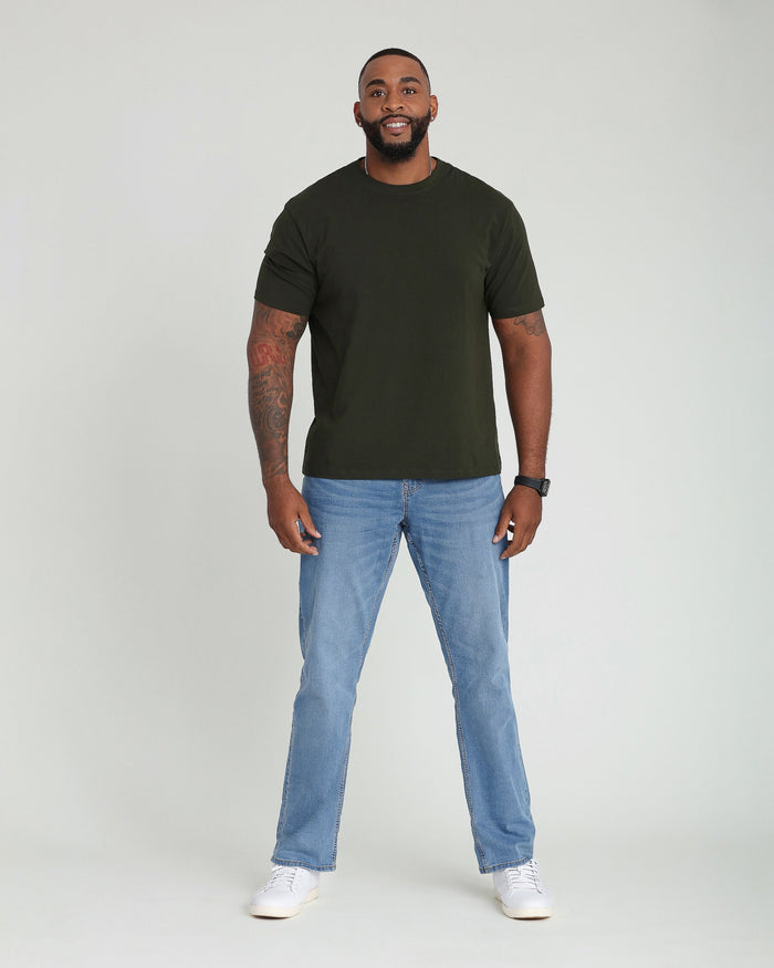 Man wearing olive green short-sleeve t-shirt and light indigo straight-leg jeans with white sneakers.