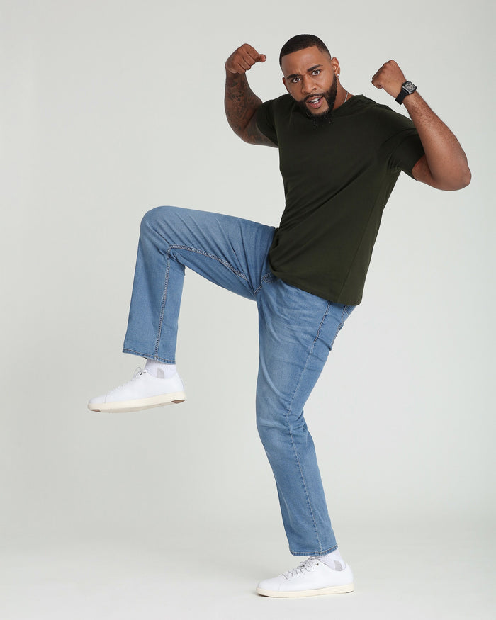 Man wearing black t-shirt and light indigo denim jeans with white sneakers.