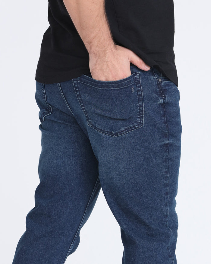 Dark blue denim jeans with relaxed fit and classic five-pocket styling, worn with black shirt.