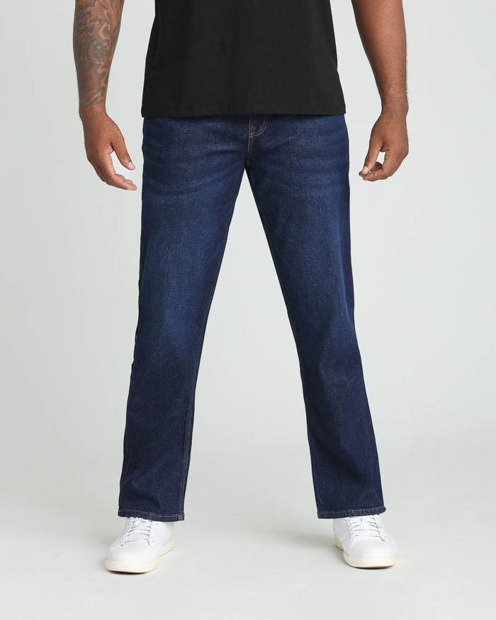 Man wearing dark blue straight-leg jeans and black t-shirt with white sneakers.
