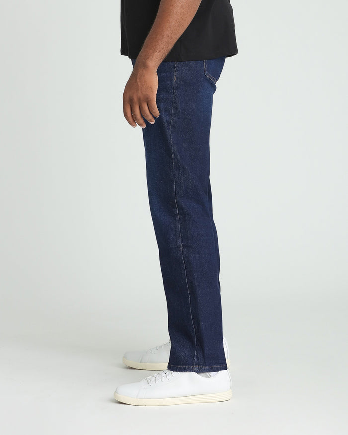 Man wearing dark blue jeans with black shirt and white sneakers, shown from side view.