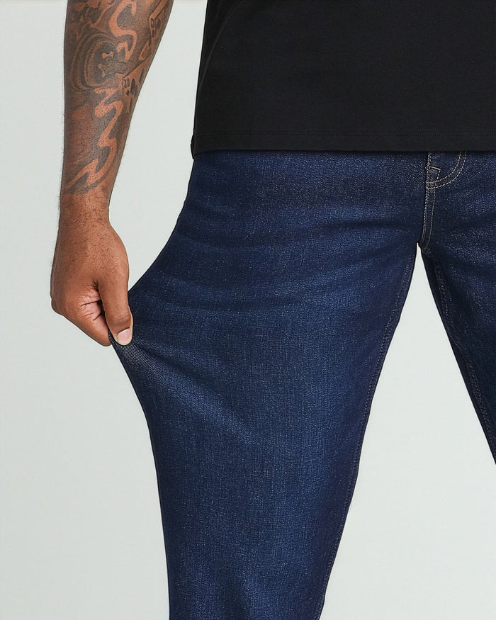 Dark blue jeans with relaxed fit through thigh, worn with black t-shirt, showing side pocket detail.
