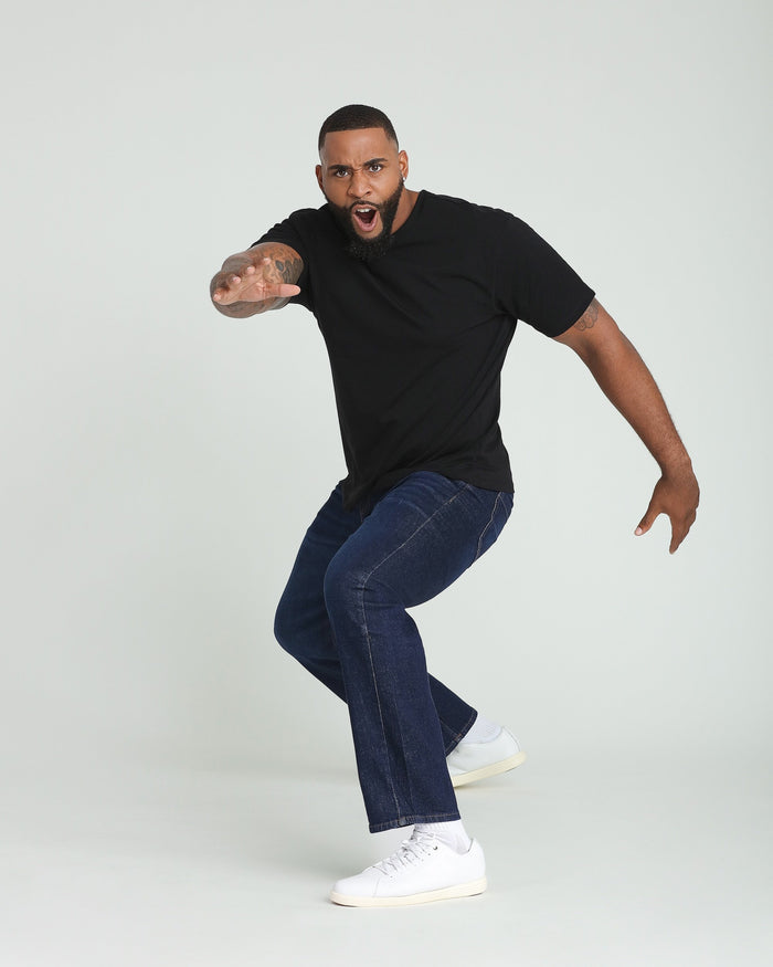 Man wearing black short-sleeve t-shirt and dark blue jeans with white sneakers.