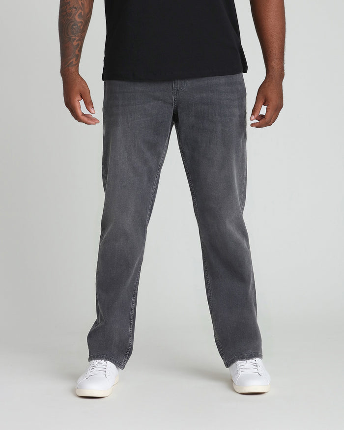 Man wearing black t-shirt and grey straight-leg jeans with white sneakers.