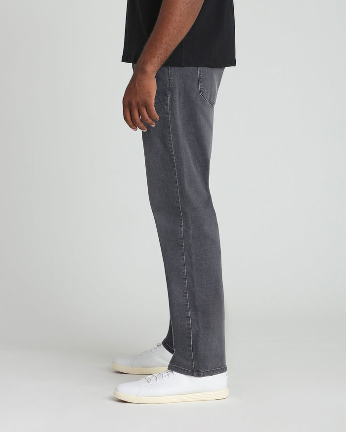 Grey denim jeans with relaxed fit, shown on model wearing black shirt and white sneakers.