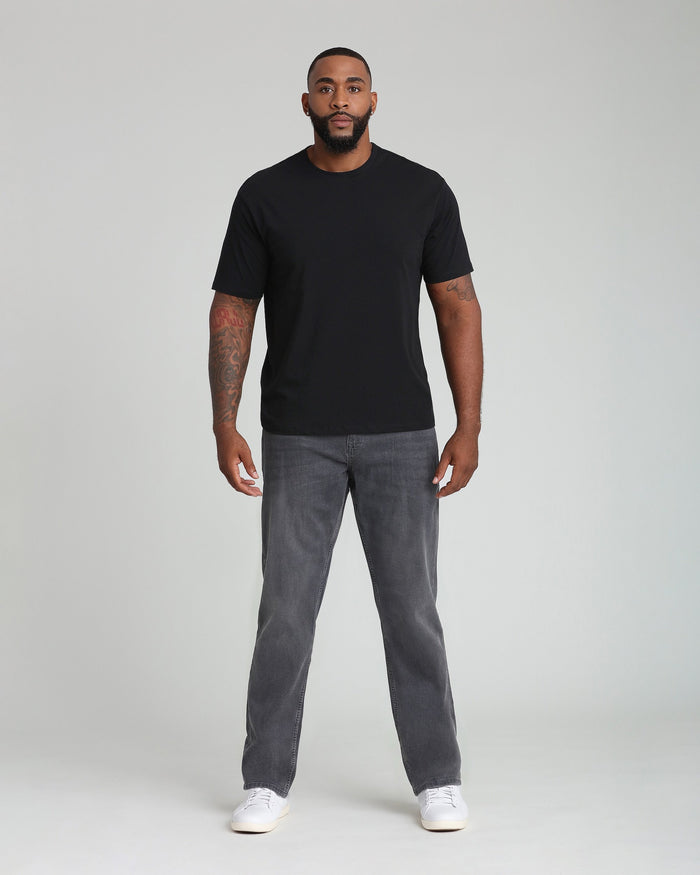 Man wearing black short-sleeve t-shirt and gray denim jeans with white sneakers.