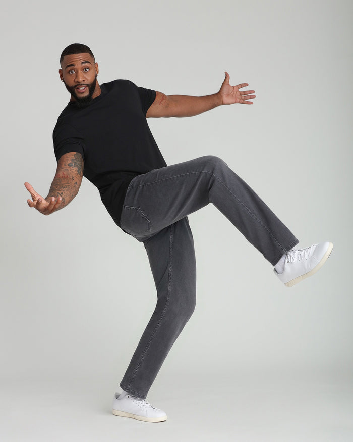 Man wearing black short-sleeve t-shirt and gray straight-leg jeans with white sneakers.