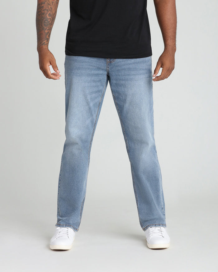 Light blue straight-fit jeans with visible stitching seams worn with black t-shirt and white canvas sneakers.
