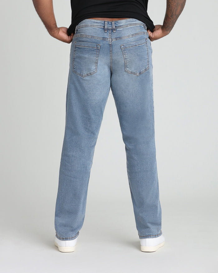 Light blue denim jeans with relaxed fit, back pocket detail, worn with black shirt and white sneakers.