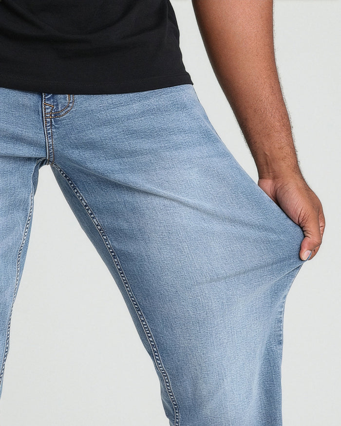 Light blue denim jeans with stitched seams worn with black shirt, shown on model from waist to thigh.