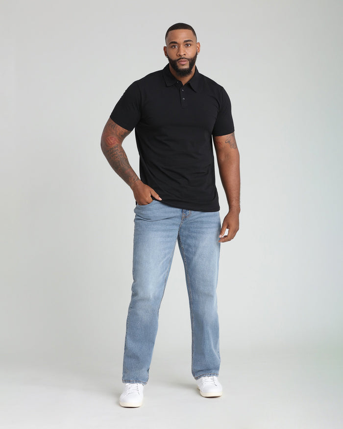 Man wearing black short-sleeve polo shirt with light blue jeans and white sneakers.