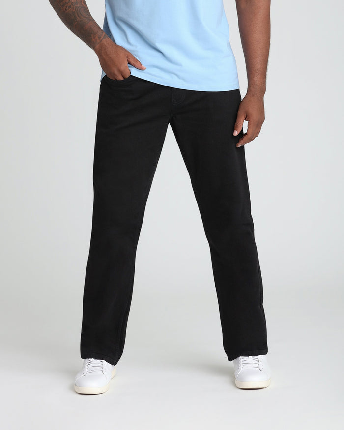 Man wearing light blue t-shirt and black jeans with white sneakers.