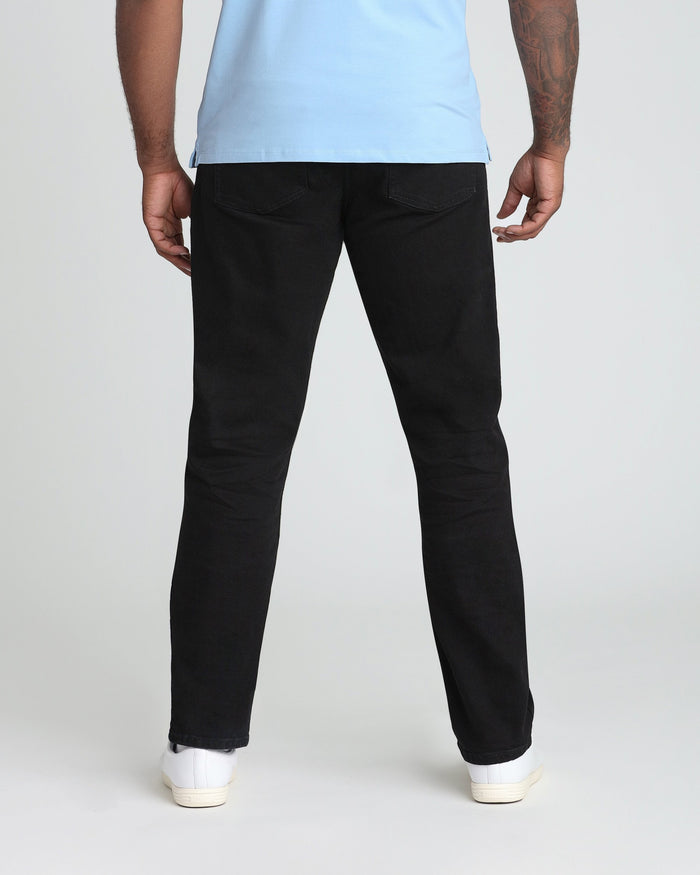 Man wearing light blue t-shirt and black denim jeans with white sneakers, shown from behind.