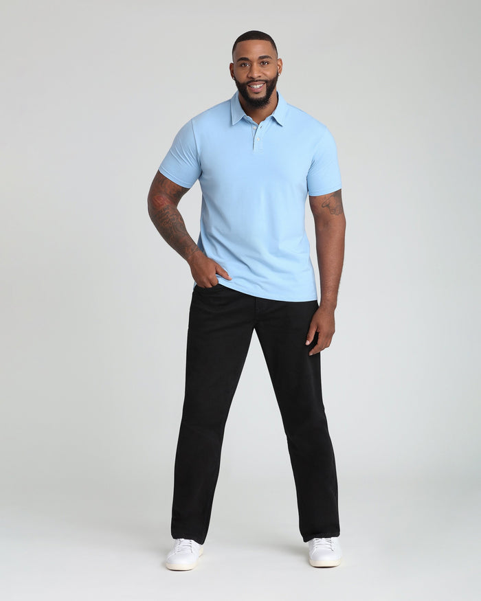 Man wearing light blue short-sleeve polo shirt and black straight-leg pants with white sneakers.