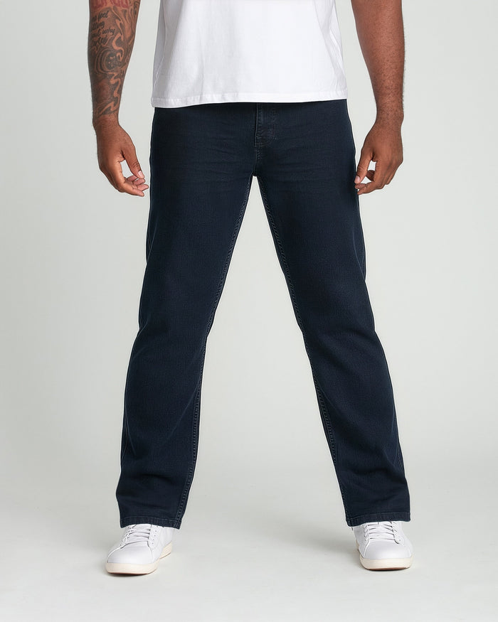 Man wearing white t-shirt and deep blue straight-leg jeans with white sneakers.