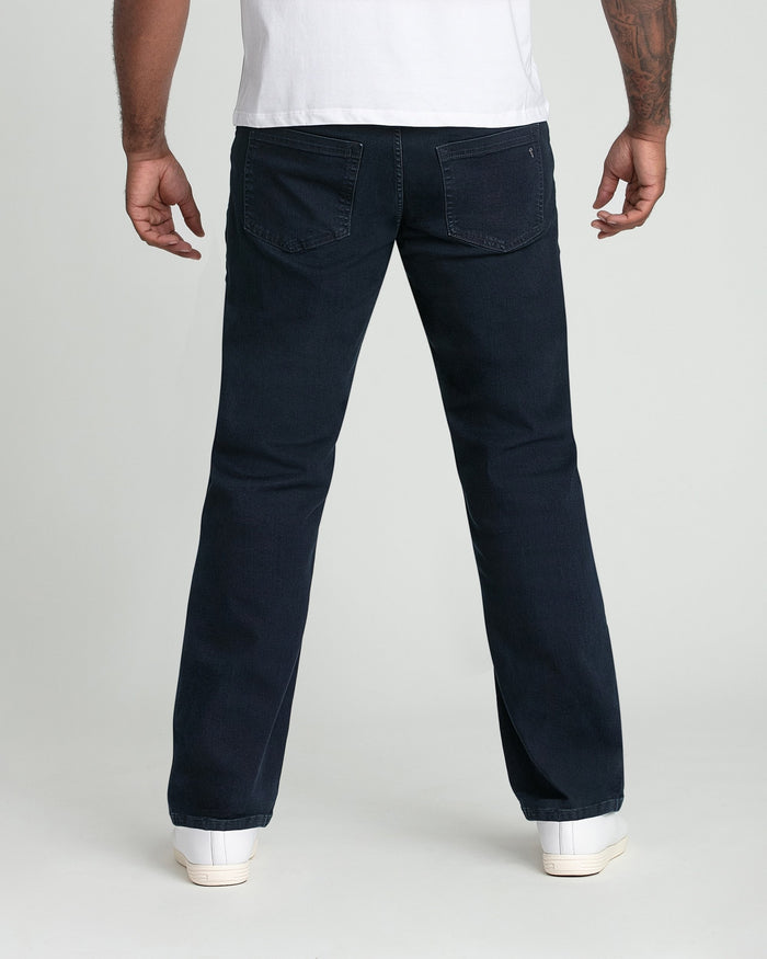 Man wearing deep blue straight-fit jeans with white t-shirt and white sneakers, shown from behind.