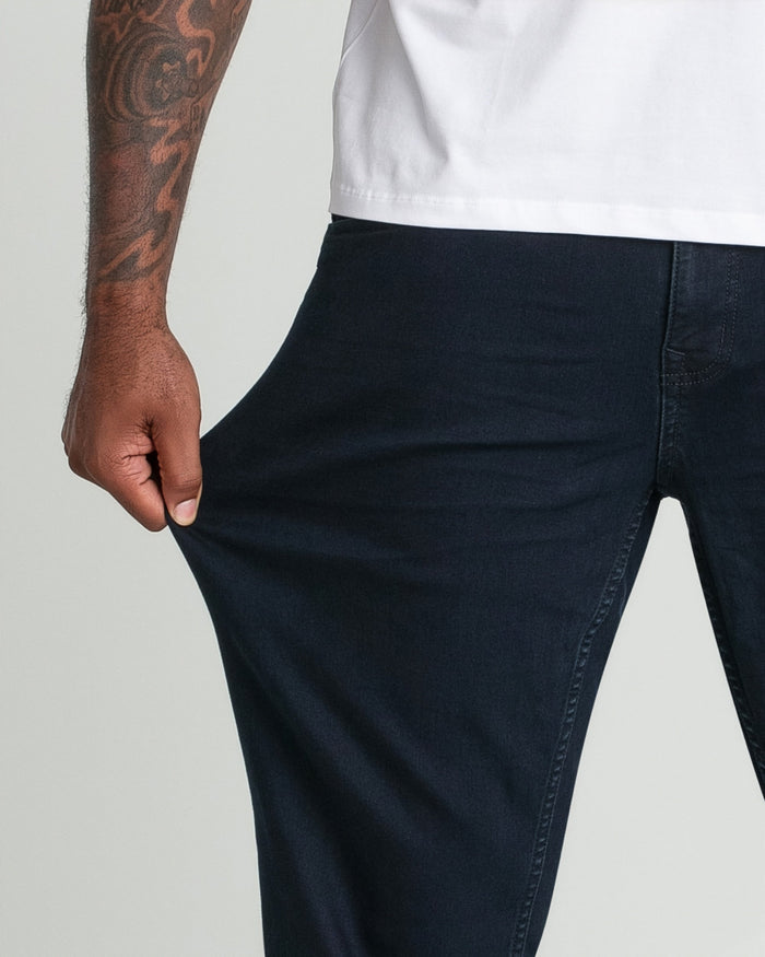 Person wearing white t-shirt and deep blue denim jeans with relaxed fit, shown from waist down.