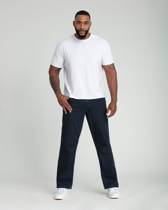 Man wearing white short-sleeve t-shirt and dark blue jeans with white sneakers.