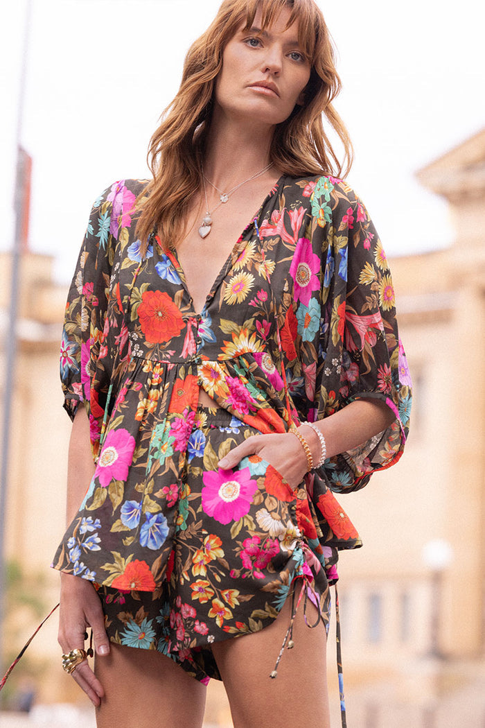Model wearing Valley of the Dolls Boho Blouse front view, V-neck tie detail and floral print on onyx