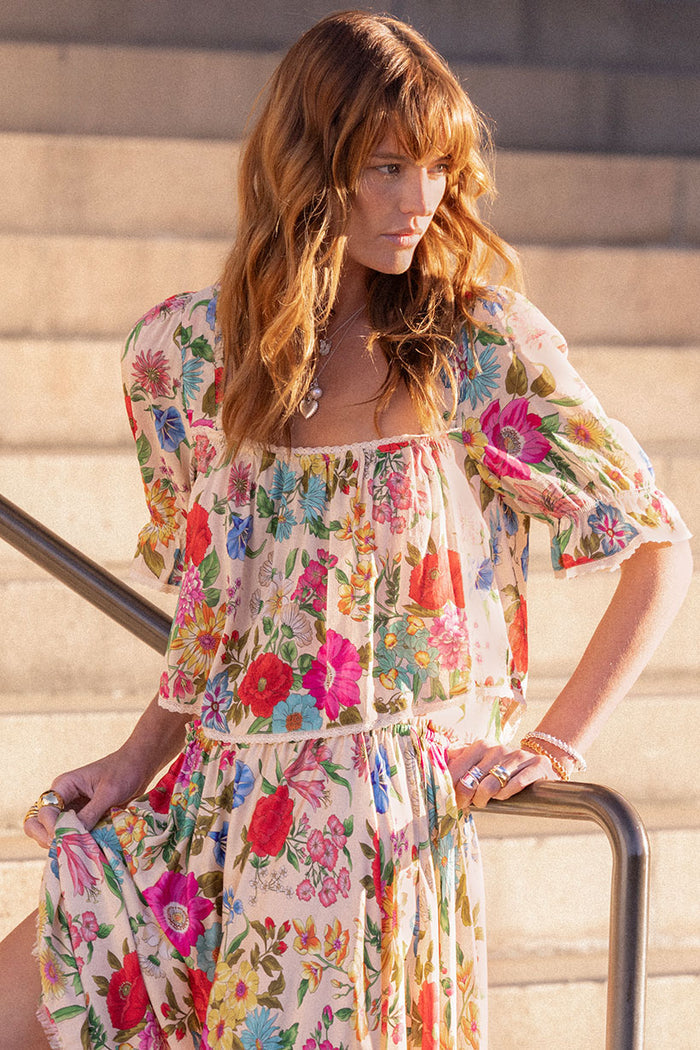 Front view of floral blouse with lace trim neckline, elastic sleeves, and cropped waist on outdoor steps