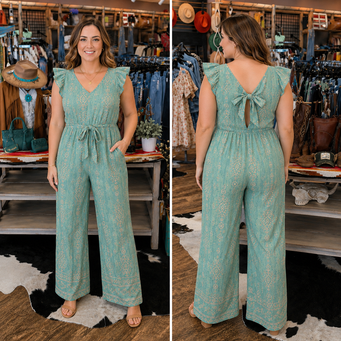 Woman wearing a teal patterned jumpsuit in a store setting.