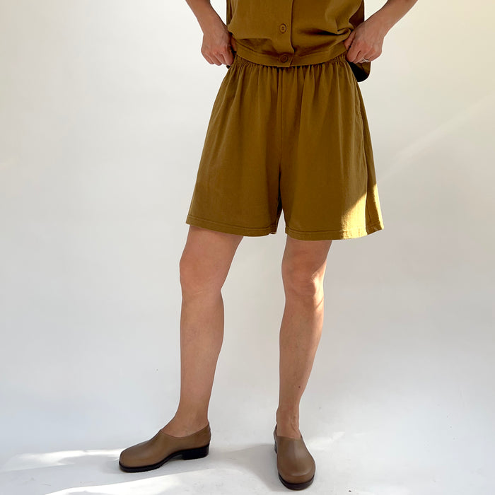 Person wearing a brown outfit with shorts and a top on a white background