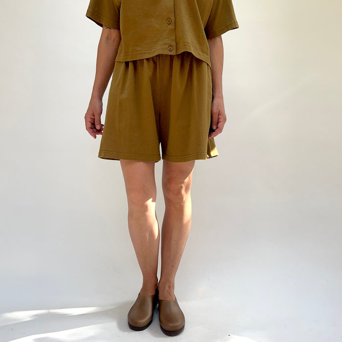 Person wearing a brown outfit with shorts and a top on a white background